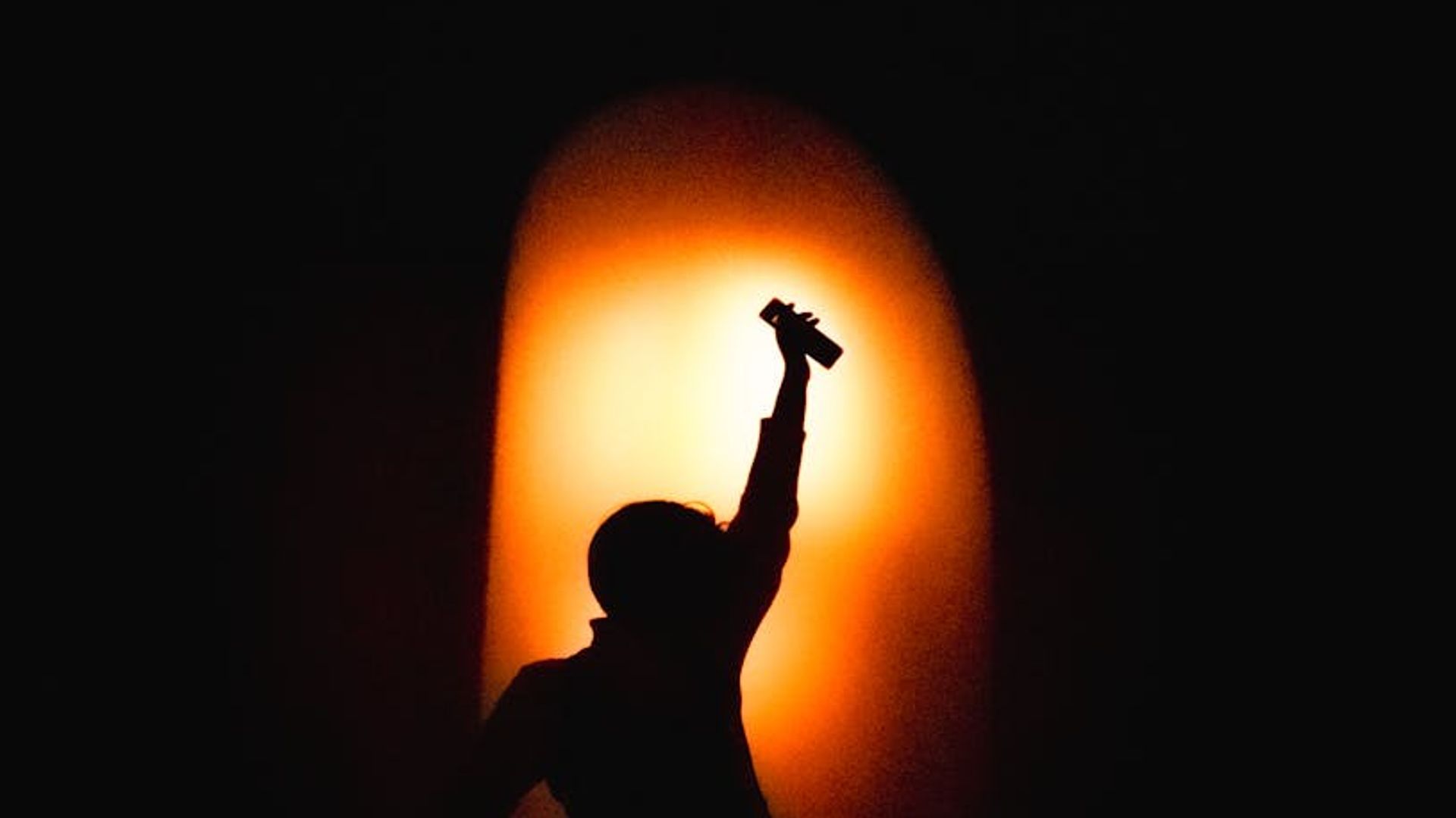 Man's silhouette in a powerful stance against a dark background.